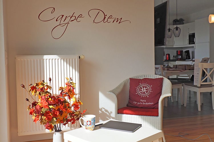 Lichtdurchflutete Sitzecke mit Schriftzug Carpe Diem an der Wand