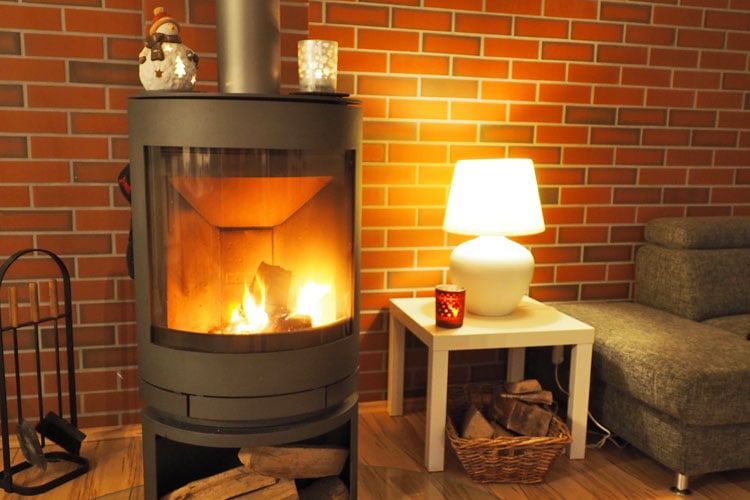 Kamin, in dem ein Feuer brennt, dazu sorgen Teelichter und eine Tischlampe für eine gemütliche Beleuchtung