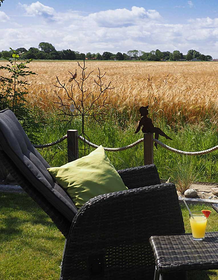 Liegesessel im Garten mit Blick auf ein weites Feld