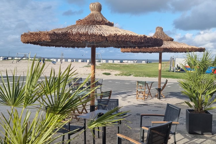 Strandbistro mit strohgedeckten Sonnenschirmen